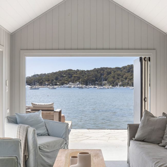 boat house living area looking out at a view of the water with grey couches